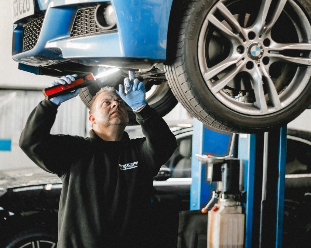 Car service technician fixing underneath a car during MOT
